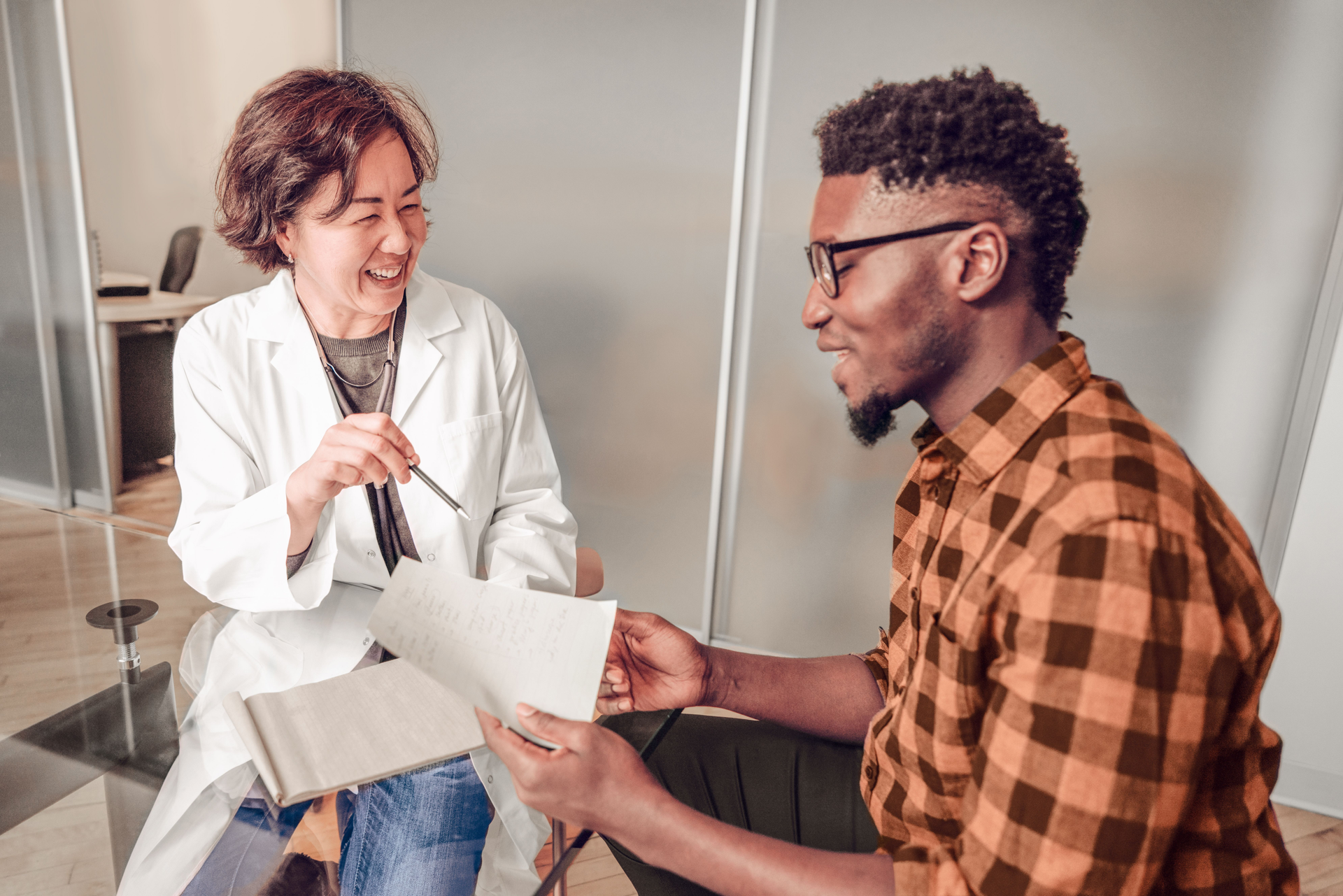 Doctor and patient sitting together and laughing, showing positive patient relationships