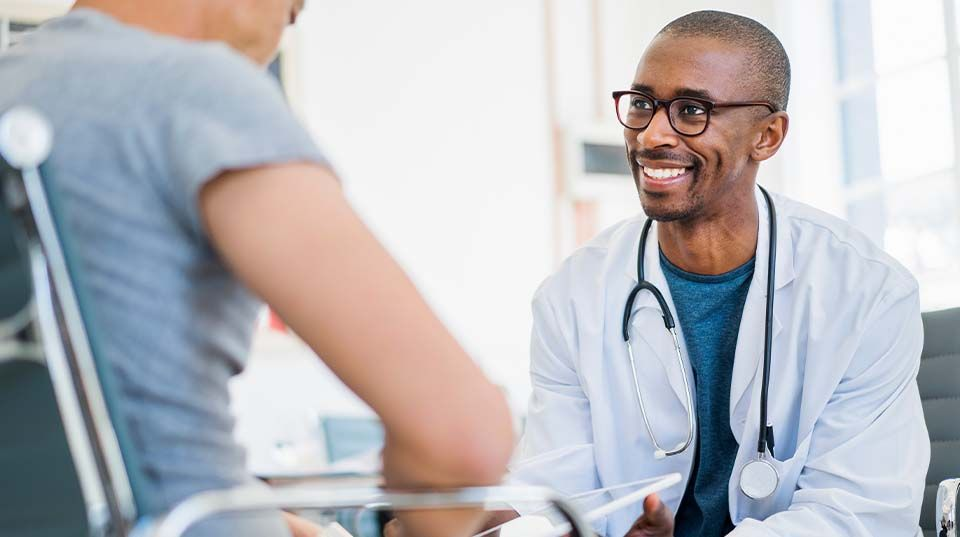 Doctor smiling while talking with a patient, representing career growth and leadership opportunities